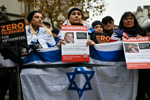 Protesters wave Israeli flags and hold photos of people held hostage by Hamas in Gaza