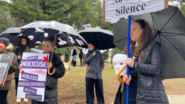 Demonstrators hold signs against what they describe as international silence over sexual violence perpetrated against Israeli women during the attack by Hamas