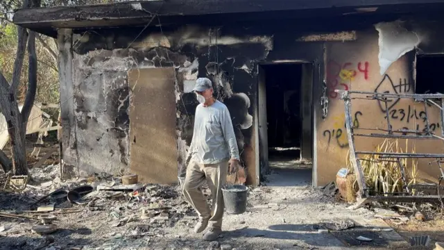 An archeologist from the Israel Antiquities Authority (IAA) sifts through the remains of burnt-out houses to look for human remains to identify victims that have been missing since the deadly October 7 attack by Hamas gunmen from the Gaza Strip, at Kibbutz Nir Oz, in southern Israel,