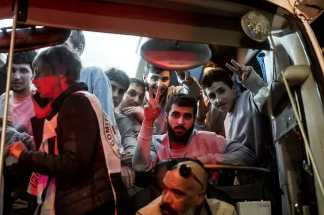 Palestinian prisoners wave from a bus as they are about to be released