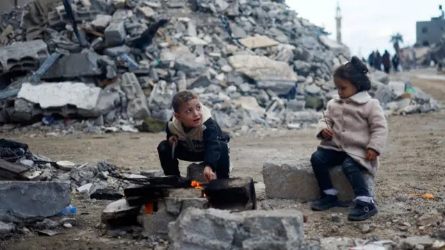 Palestinian children sit by the fire next to the rubble of a house hit in an Israeli strike during the conflict, amid a temporary truce between Hamas and Israel, in Khan Younis in the southern Gaza Strip November 27, 2023. REUTERS/Mohammed Salem