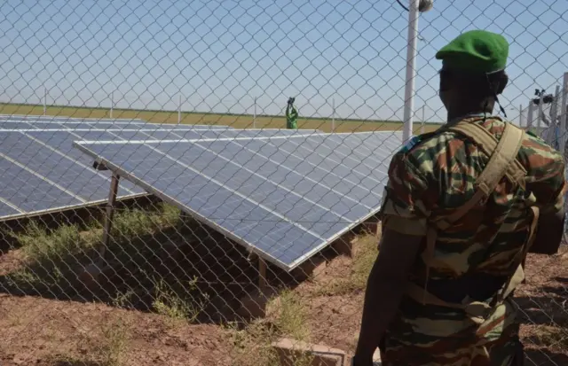 A member of the Nigerien Military is stationed in front of solar panels that pump borehole water to irrigate the site of the Irhazer project, financed by France near Agadez, in the northern desert of Niger, on November 8, 2019.