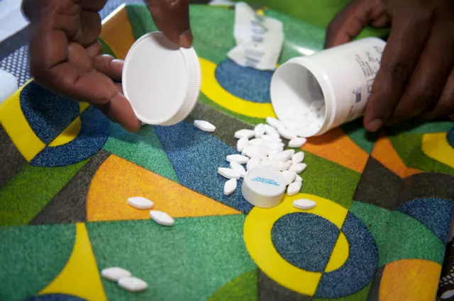 A village health worker checking the antiretroviral drugs for a patient