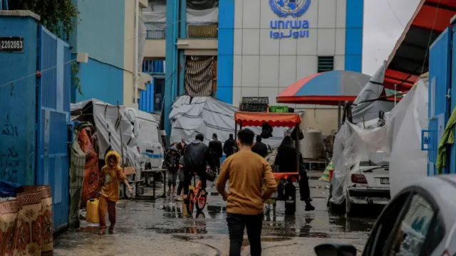 Palestinians walk at the entrance of a UNWRA school used as shelter in Gaza City on November 27, 2023, on the fourth day of a truce in fighting between Israel and Hamas.