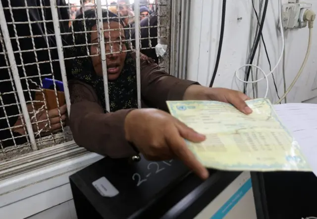 Woman showing a card through metal bars