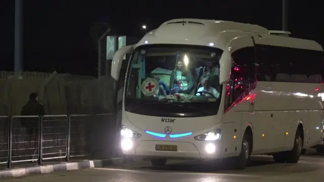 A white bus with Red Cross branding parked on a road