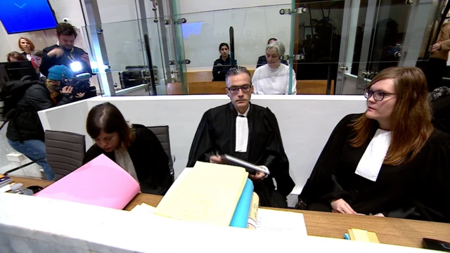 Barristers sitting in front of Monique Olivier who is behind glass