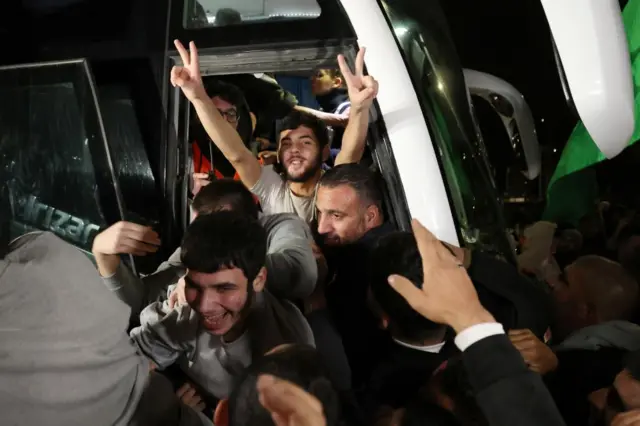 Released prisoners celebrate as they get off the bus, surrounded by crowds