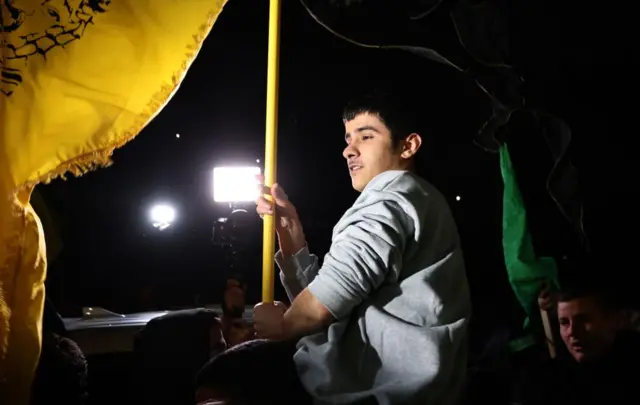 A released prisoner holding a flag and being lifted