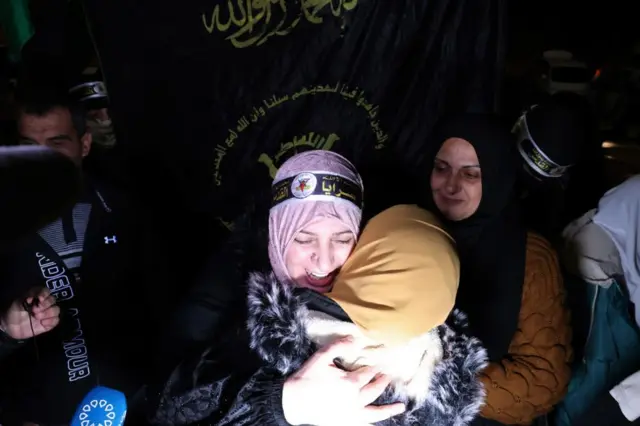 A woman, wearing a PFLP headband, hugs another woman after being released