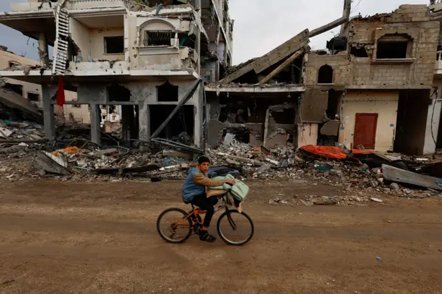 A Palestinian rides a bicycle next to the rubble of a house hit in an Israeli strike during the conflict, amid a temporary truce between Hamas and Israel, in Khan Younis in the southern Gaza Strip 27 November 2023. REUTERS/Mohammed Salem. Uploaded 29 November