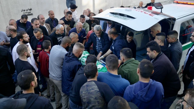 A body is loaded from an ambulance in Jenin