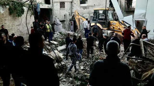 People walk through an area devastated by a strike in Jenin