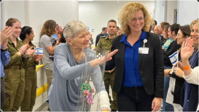 Adar waves to staff who line a hospital hallway with flags