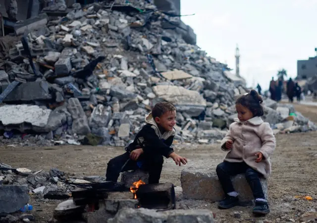 Palestinian children sit by the fire next to the rubble of a house hit in an Israeli strike during the conflict, amid a temporary truce between Hamas and Israel, in Khan Younis in the southern Gaza Strip 27 November 2023. Uploaded 29 November