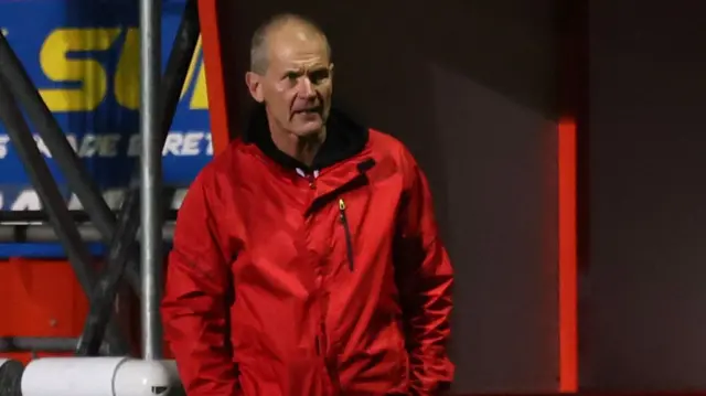 Sheppey manager Ernie Batten stands next to the dugout