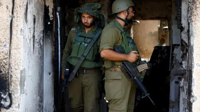 Soldiers look on near a destroyed home, following the deadly October 7 attack by Hamas gunmen from the Gaza Strip, in Kibbutz Kfar Aza, southern Israel November 2, 2023.