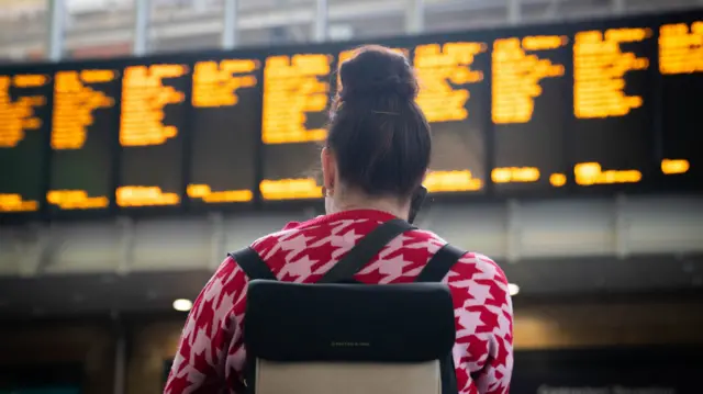 Woman looking at train time board