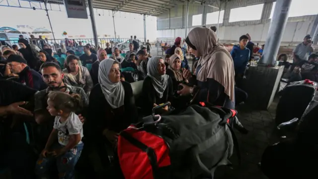 Citizens with foreign passports wait to travel through the Rafah crossing