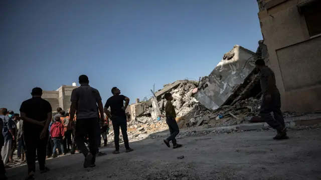 Palestinians search for bodies and survivors in the rubble of a residential building in Khan Younis, southern Gaza