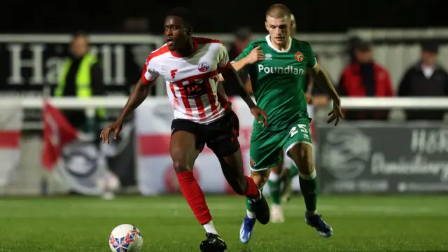 A Sheppey player runs with the ball and holds off Walsall