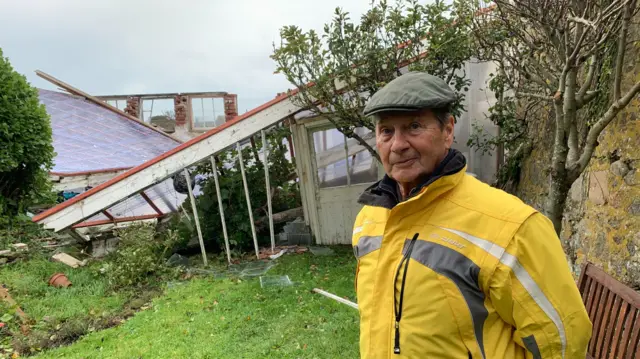 Royston James next to his destroyed greenhouse