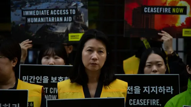 People hold signs that read 'ceasefire' in both Korean and English