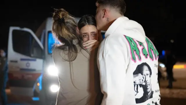 Mia holds her mother's shoulder as the pair hug while her brother kisses her on the forehead.