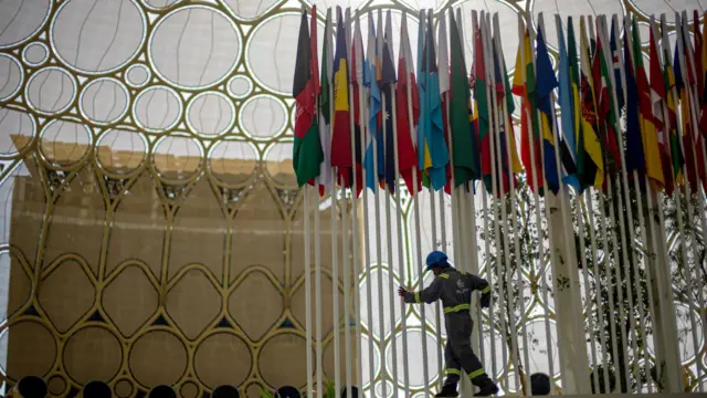 A worker adjusts flags at the summit