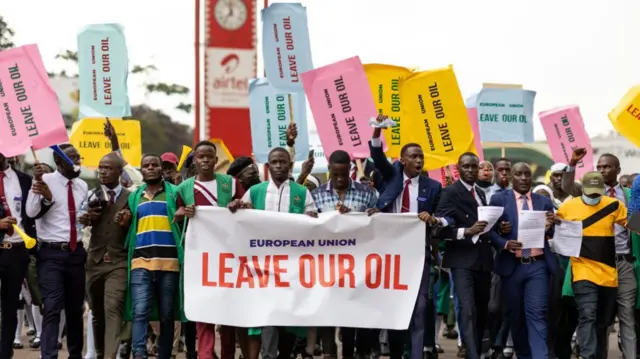 Members of the Uganda National Students Association hold up signs reading "European Union Leave Our Oil" as they participate in a rally on September 29, 2022 in Kampala, Uganda.