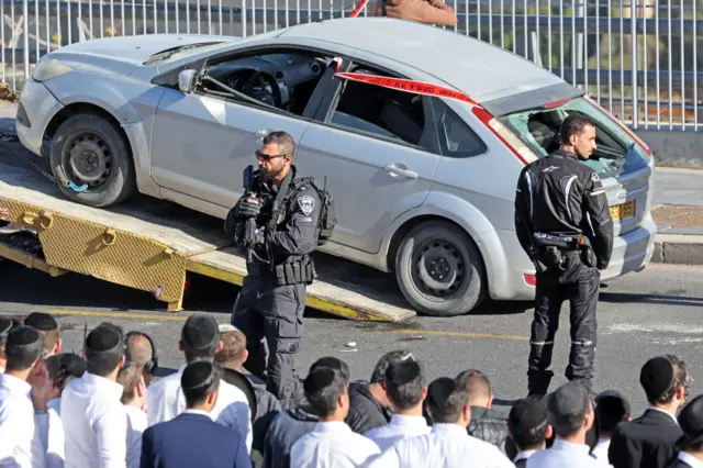 Two Israeli police officers in front of car reportedly used by attackers in Jerusalem