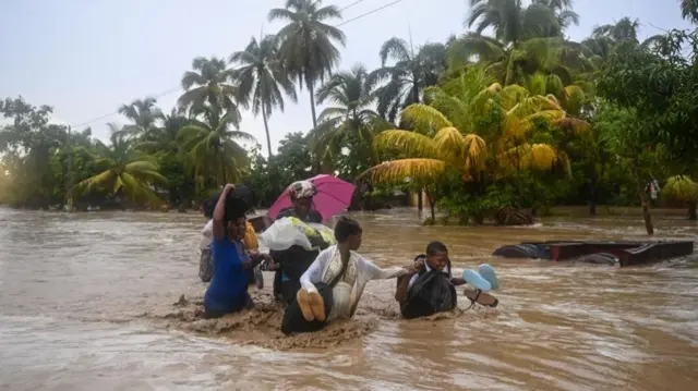 Residents cross a submerged road in Haiti after heavy rainfall, June 2023