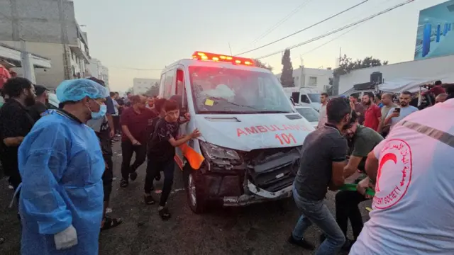 Palestinians pull a damaged ambulance outside the entrance of the Al-Shifa hospital