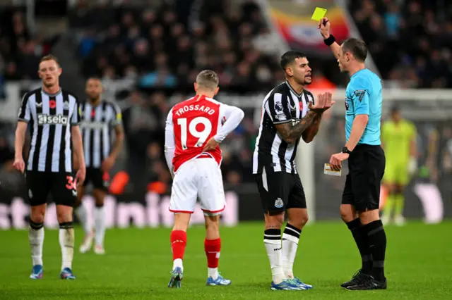 Guimaraes protests as he is shown a yellow card by the ref.