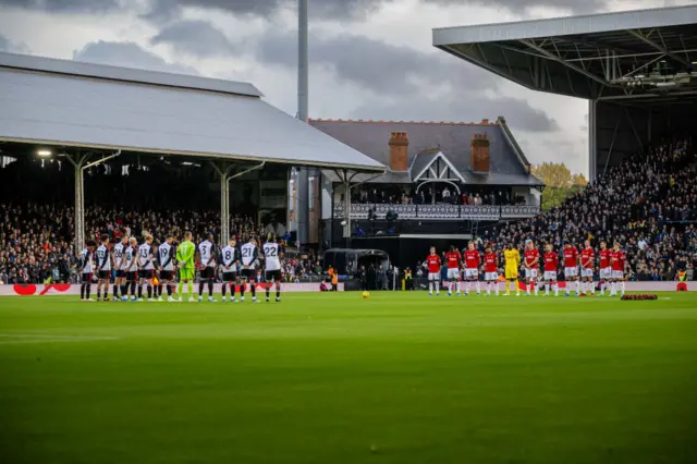 Players gather around the centre circle for a minute's silence at Craven Cottage