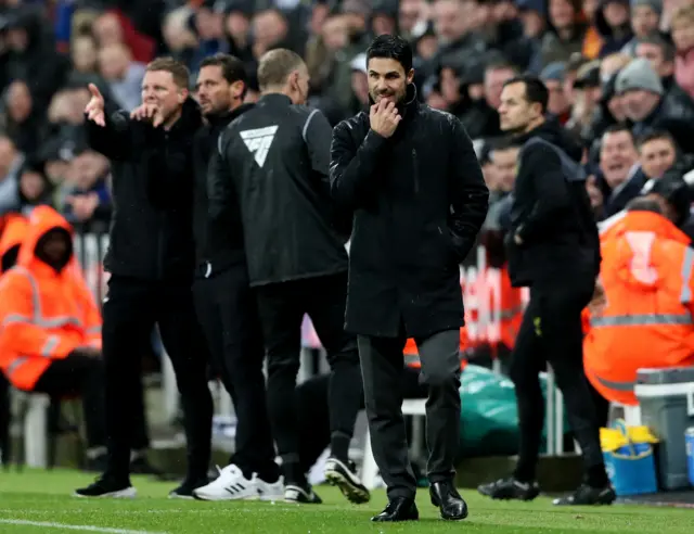 Arteta scratches his chin while watching on from the touchline.