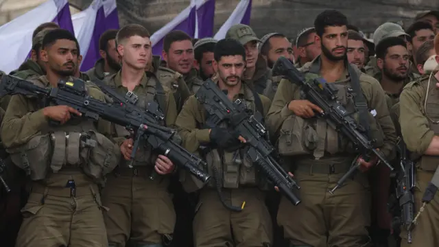 Israeli soldiers stand in formation while being addressed by the defence minister near the Gaza border