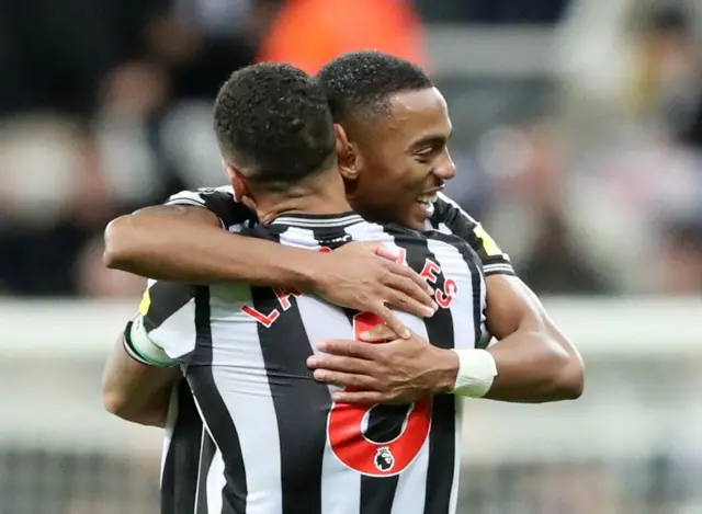 Willock and Lascelles embrace after Newcastle's win is confirmed.