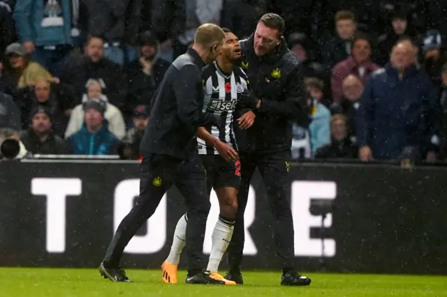 Murphy is helped off the pitch by the medical staff.