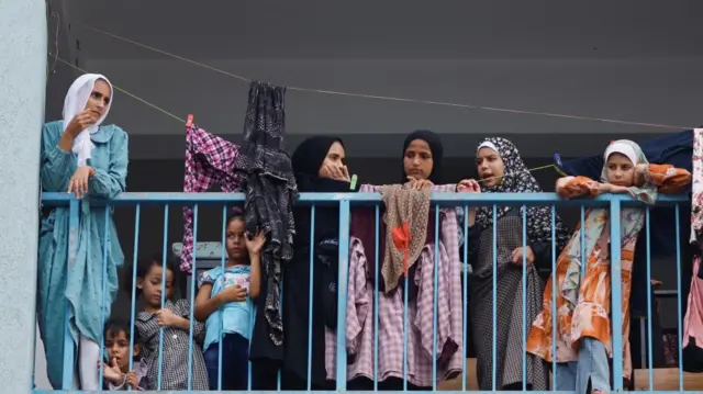 Palestinians, who have fled their homes due to Israeli strikes, watch a nearby Israeli strike as they take shelter in a UN-run school, in Khan Younis