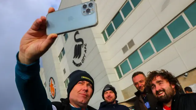 Fans take a selfie outside the Swansea City stadium.