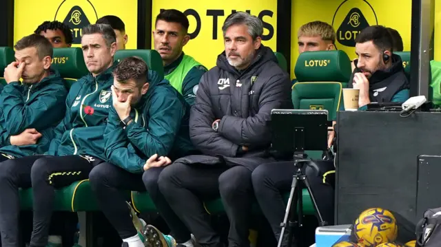 David Wagner (second right) sits with his arms folded in the dugout