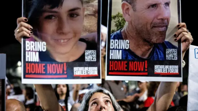 A person holds pictures during a protest to demand the immediate release of hostages held in Gaza who were seized in the October attack by Hamas gunmen