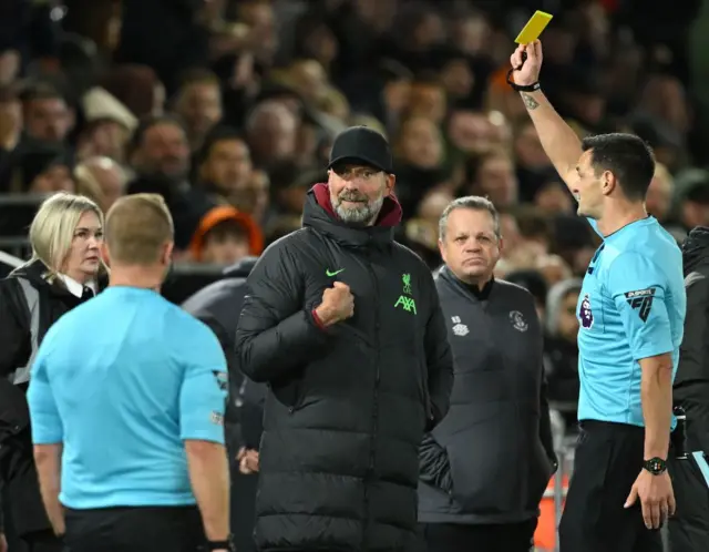 Andy Madley shows a yellow card to Jurgen Klopp