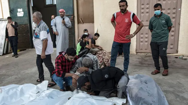 Palestinians mourn over the bodies of relatives killed in the blast at al-Maghazi camp