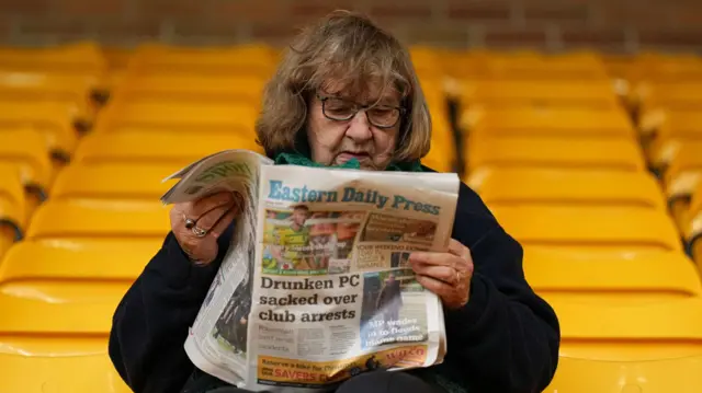 Norwich City fan reads newspaper