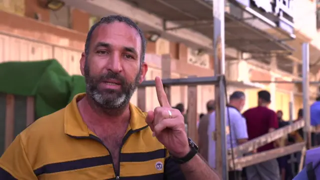 Man near queue for bread in Khan Younis in Gaza