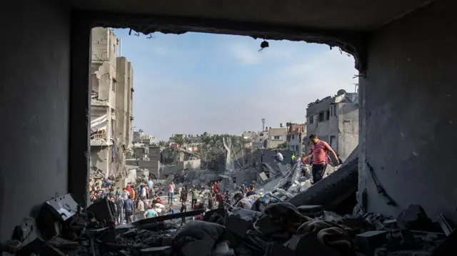 Palestinians search for bodies and survivors among the rubble of a residential building at the Maghazi refugee camp