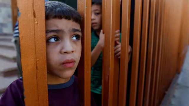 A child looks on from behind a gate in Khan Younis, Gaza