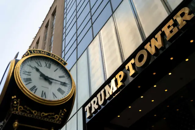 View of Trump Tower from low angle looking up with clock tower in view and light reflecting off large sign